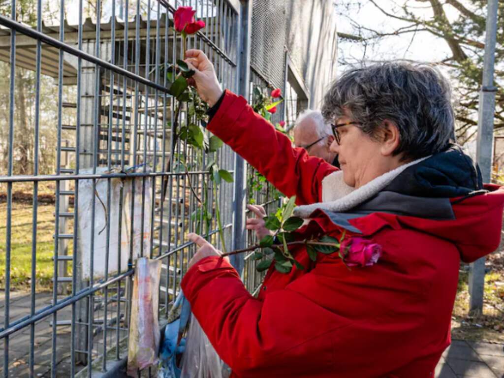 Tetske Haalboom steekt bloemen tussen de metalen tralies.
Beeld: Mel Boas